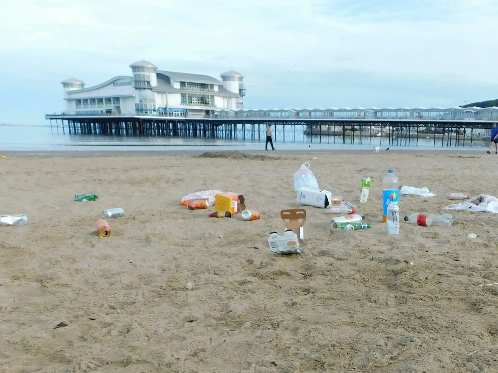 Cans, bottles and bags left on the sand at Weston-super-Mare, with the Grand Pier behind